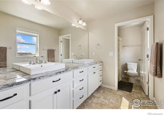 bathroom featuring double vanity, toilet, and baseboards