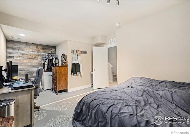 bedroom with wooden walls, a closet, a desk, an accent wall, and carpet flooring