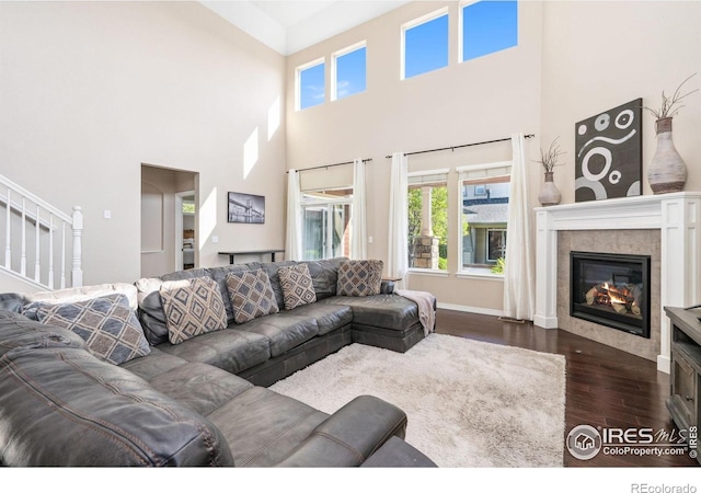 2150 Blue Yonder Way, Fort Collins, CO 80525 - living room with dark wood-type flooring, a tile fireplace, a towering ceiling, baseboards, and stairs
