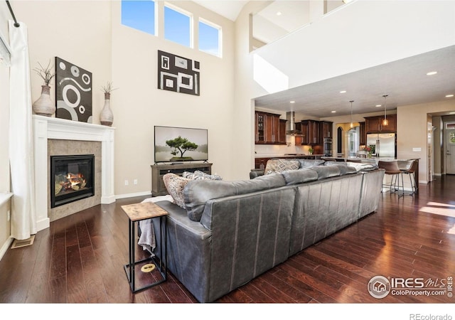 2150 Blue Yonder Way, Fort Collins, CO 80525 - living room featuring dark wood-style flooring, a tile fireplace, recessed lighting, baseboards, and a high ceiling