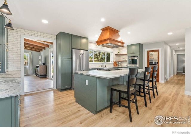 kitchen featuring green cabinets, appliances with stainless steel finishes, healthy amount of natural light, light wood-style flooring, and recessed lighting