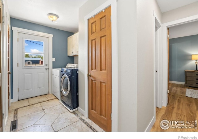 clothes washing area with independent washer and dryer, cabinet space, and baseboards