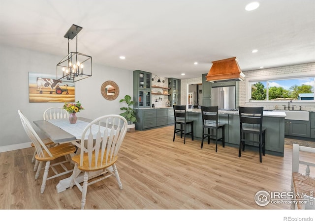dining space featuring baseboards, light wood-type flooring, recessed lighting, and a chandelier