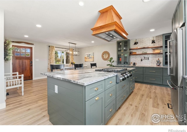 kitchen with appliances with stainless steel finishes, a center island, light wood-type flooring, island range hood, and recessed lighting