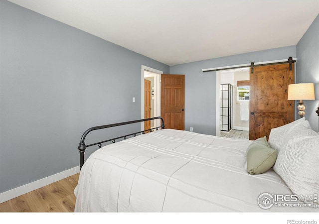 bedroom featuring wood finished floors, baseboards, and a barn door