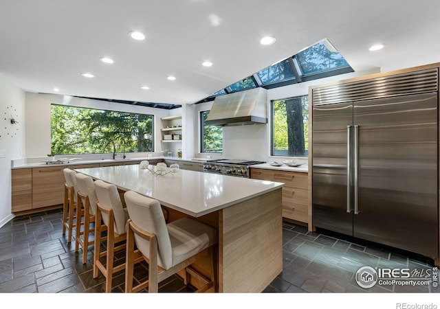 505 Geneva Ave, Boulder, CO 80302 - kitchen featuring stainless steel built in fridge, wall chimney range hood, stone tile floors, light countertops, and healthy amount of natural light