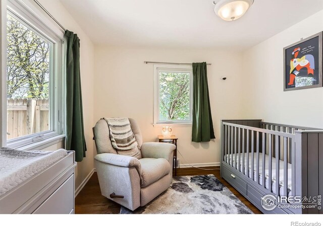 1136 Venice St, Longmont, CO 80501 - bedroom featuring dark wood finished floors, a crib, and baseboards