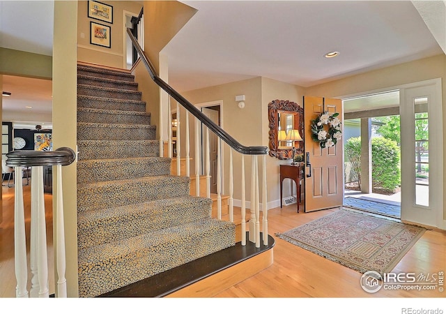 foyer entrance featuring stairway, wood finished floors, baseboards, and recessed lighting