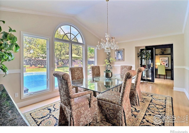 dining area featuring a chandelier, plenty of natural light, wood finished floors, vaulted ceiling, and crown molding