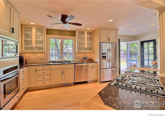 kitchen with stainless steel appliances, a sink, light wood-style floors, decorative backsplash, and recessed lighting