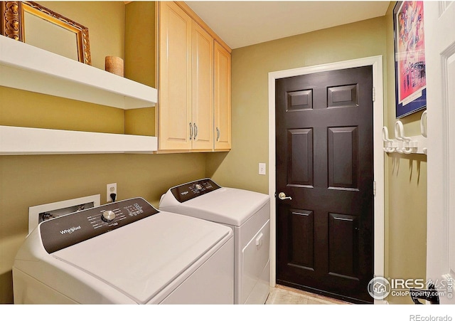 clothes washing area with washing machine and dryer and cabinet space