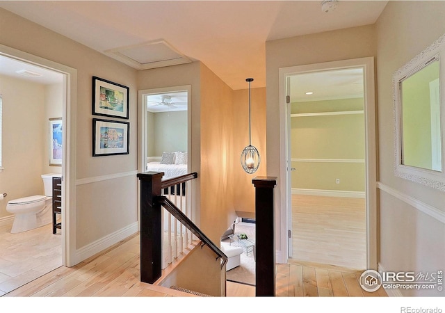 corridor featuring an upstairs landing, light wood-style flooring, and baseboards