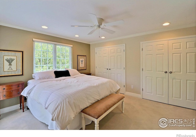 bedroom featuring light carpet, recessed lighting, two closets, baseboards, and ornamental molding