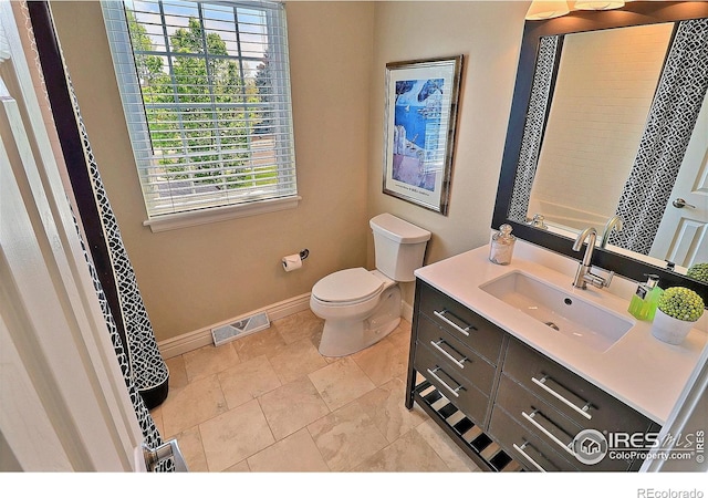 bathroom featuring baseboards, healthy amount of natural light, toilet, and vanity