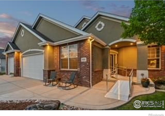 view of front of house with an attached garage, brick siding, and driveway