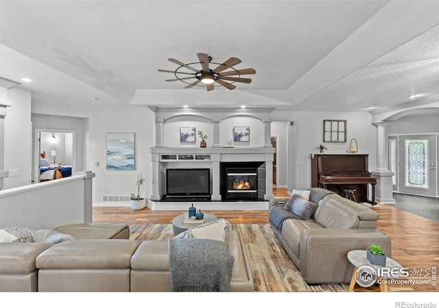 living area featuring a ceiling fan, wood finished floors, baseboards, ornate columns, and recessed lighting