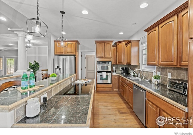 kitchen with a sink, appliances with stainless steel finishes, tile counters, a center island, and tasteful backsplash