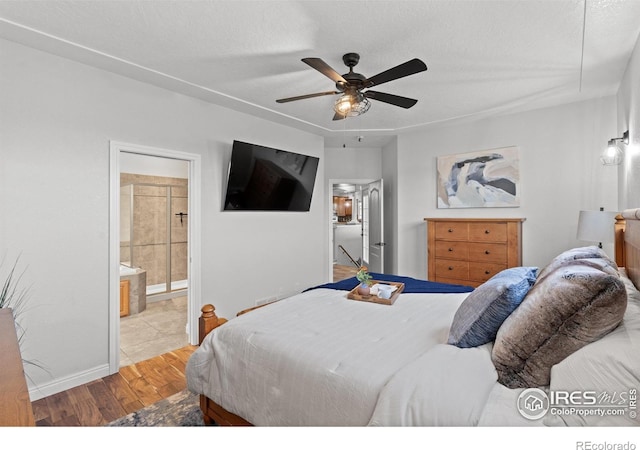 bedroom with wood finished floors, baseboards, ensuite bathroom, ceiling fan, and a textured ceiling