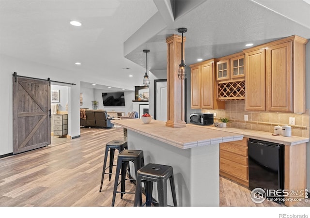 kitchen with fridge, a breakfast bar, light wood-type flooring, recessed lighting, and black microwave