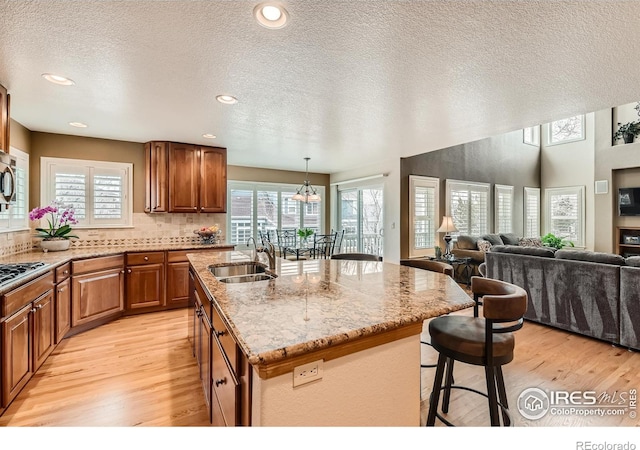 14180 Whitney Cir, Broomfield, CO 80023 - kitchen featuring a sink, light wood finished floors, a kitchen breakfast bar, light stone countertops, and a textured ceiling