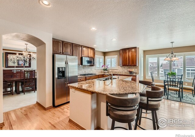 14180 Whitney Cir, Broomfield, CO 80023 - kitchen with stainless steel appliances, a chandelier, arched walkways, a sink, and light wood finished floors
