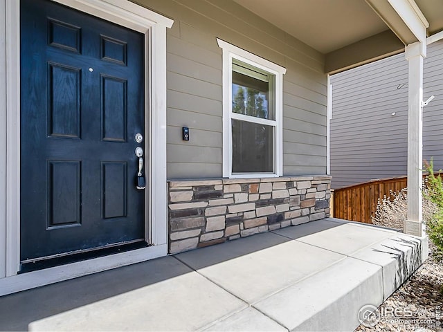 property entrance with a porch and stone siding