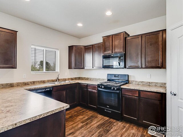 kitchen with black appliances, a sink, dark brown cabinets, dark wood-type flooring, and recessed lighting