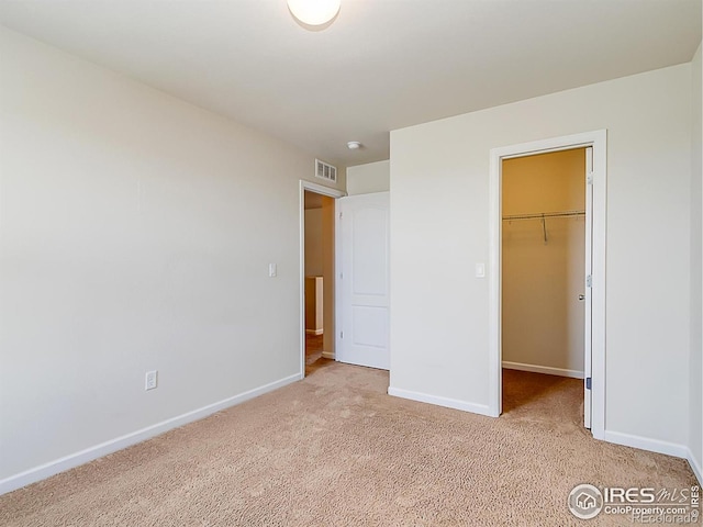 unfurnished bedroom with light carpet, baseboards, a spacious closet, and a closet