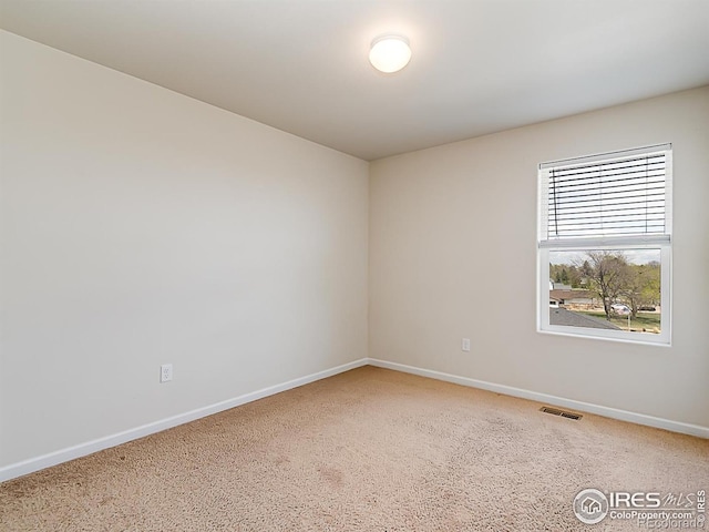 empty room featuring baseboards and light colored carpet