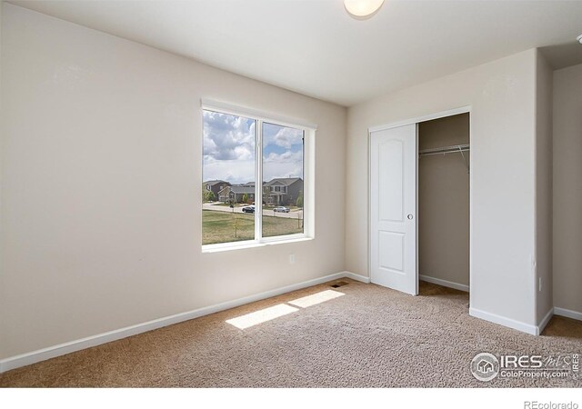 unfurnished bedroom with carpet floors, baseboards, and a closet