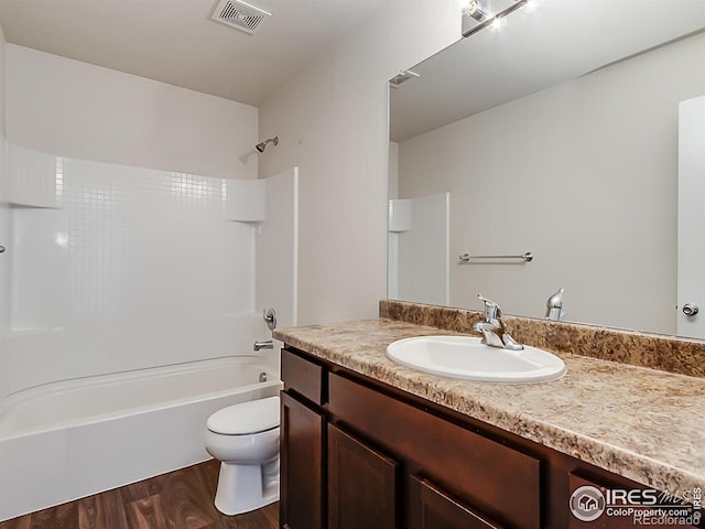 bathroom featuring wood finished floors, toilet, shower / bath combination, and vanity