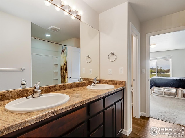 ensuite bathroom with wood finished floors, double vanity, and a shower with curtain