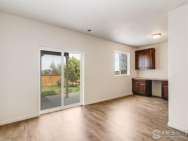 unfurnished living room with baseboards, plenty of natural light, and light wood-type flooring