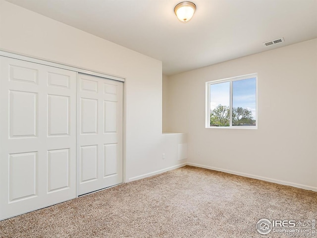 unfurnished bedroom with carpet, a closet, and baseboards