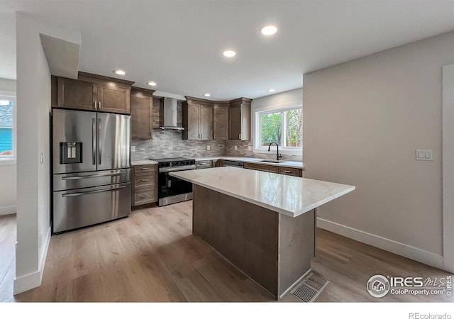 5978 Scotswood Ct, Boulder, CO 80301 - kitchen with stainless steel appliances, wall chimney range hood, a sink, tasteful backsplash, and light wood-type flooring