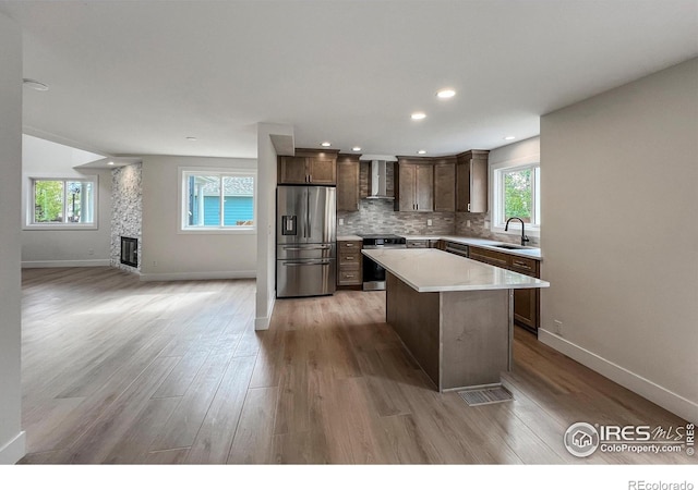 5978 Scotswood Ct, Boulder, CO 80301 - kitchen with appliances with stainless steel finishes, wall chimney exhaust hood, light wood-style flooring, a center island, and recessed lighting