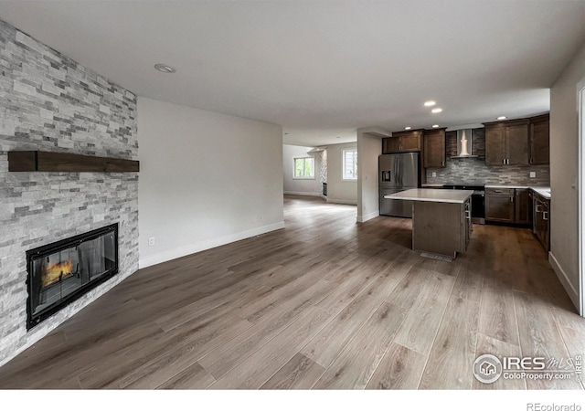 5978 Scotswood Ct, Boulder, CO 80301 - kitchen with stainless steel appliances, wall chimney exhaust hood, open floor plan, a center island, and dark brown cabinetry