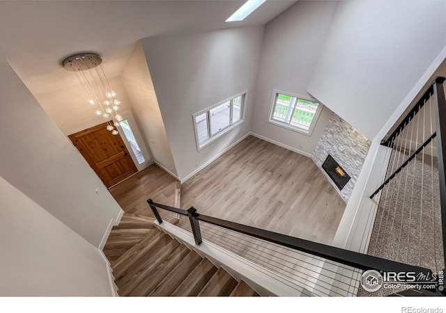 5978 Scotswood Ct, Boulder, CO 80301 - stairway featuring a high ceiling, wood finished floors, a stone fireplace, a skylight, and baseboards