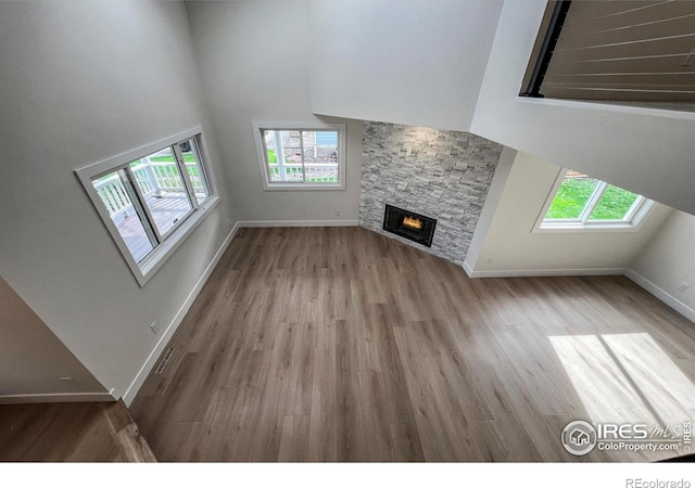 5978 Scotswood Ct, Boulder, CO 80301 - unfurnished living room with wood finished floors, a fireplace, a high ceiling, baseboards, and a skylight