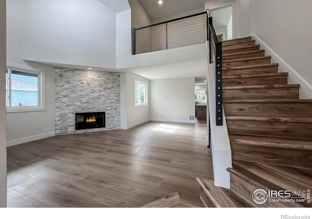 5978 Scotswood Ct, Boulder, CO 80301 - unfurnished living room featuring stairs, a stone fireplace, wood finished floors, baseboards, and a towering ceiling