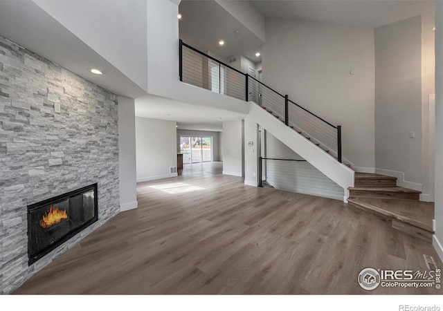 5978 Scotswood Ct, Boulder, CO 80301 - unfurnished living room with baseboards, a stone fireplace, wood finished floors, recessed lighting, and stairs