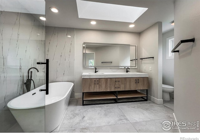 5978 Scotswood Ct, Boulder, CO 80301 - bathroom featuring a skylight, a freestanding bath, double vanity, recessed lighting, and toilet