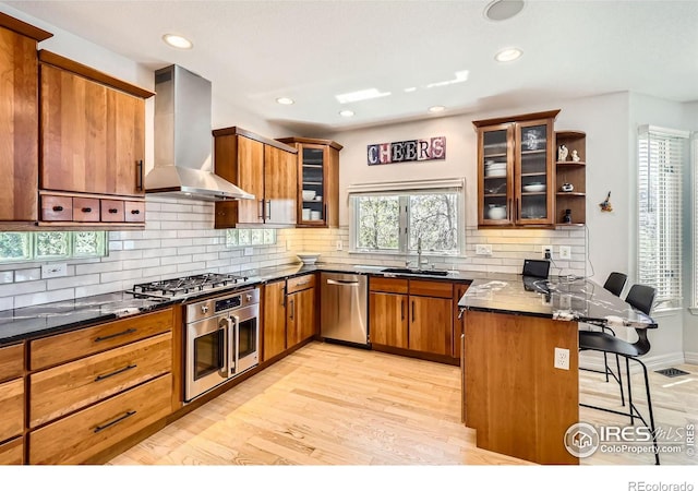 933 Xenon Ct, Golden, CO 80401 - kitchen with range hood, appliances with stainless steel finishes, a peninsula, brown cabinets, and a kitchen breakfast bar