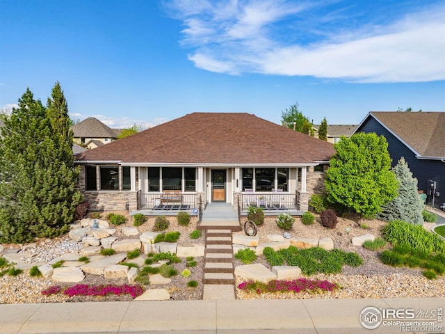 view of front of house featuring covered porch, stone siding, and roof with shingles