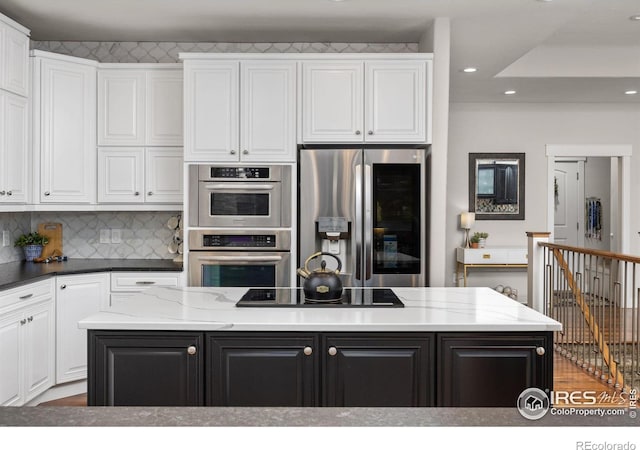 kitchen with stainless steel appliances, white cabinetry, a kitchen island, recessed lighting, and backsplash
