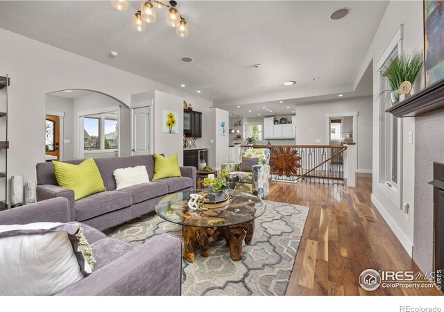 living room with arched walkways, wood finished floors, and recessed lighting