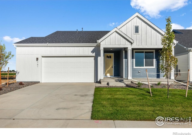 view of front of house featuring an attached garage, concrete driveway, board and batten siding, a front lawn, and a shingled roof