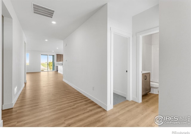 corridor featuring light wood-style flooring, recessed lighting, and baseboards