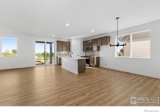 kitchen featuring light countertops, appliances with stainless steel finishes, open floor plan, baseboards, and light wood-type flooring