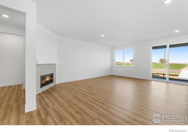 unfurnished living room with a fireplace, recessed lighting, light wood finished floors, and baseboards
